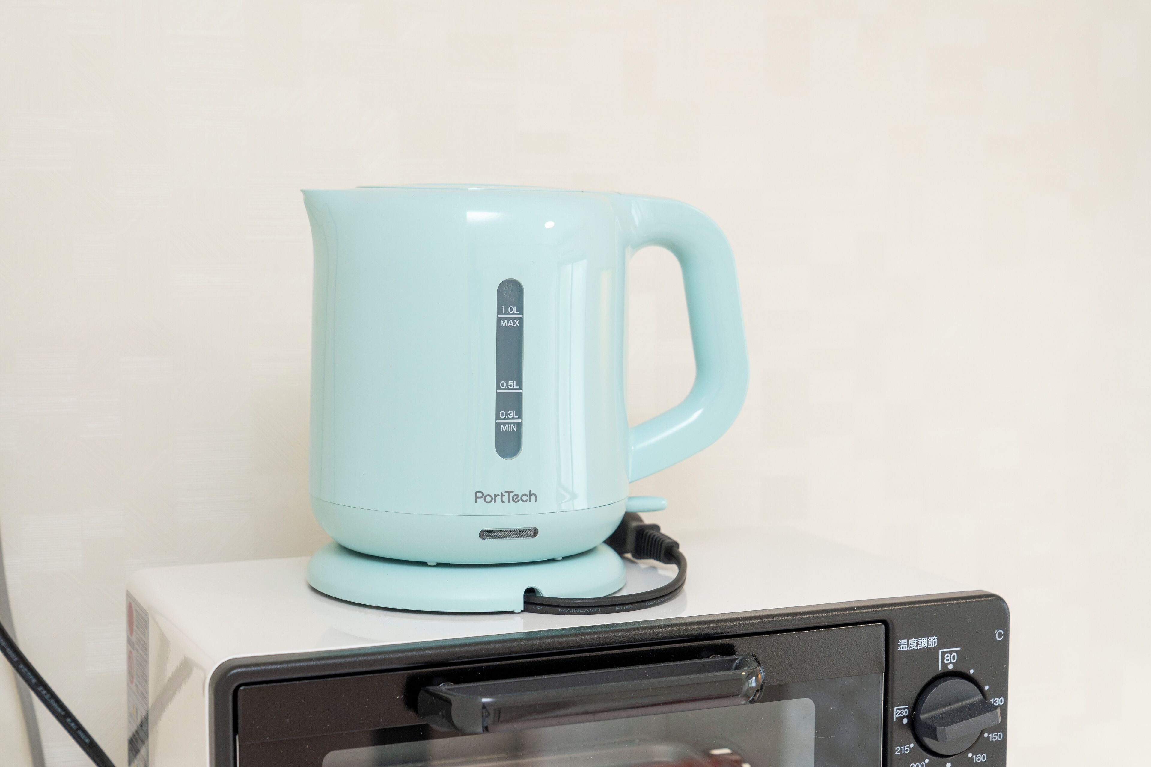 A light blue electric kettle on a white box with a black control panel.
