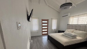 Een slaapkamer met een bed, nachtkastje, wandlamp en plafondventilator.