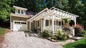 Ein zweistöckiges Haus mit überdachter Veranda, Garage und einem Schotterweg.