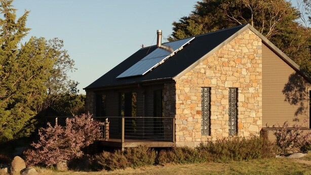 A stone house with a sloped roof, a chimney, and a small porch.