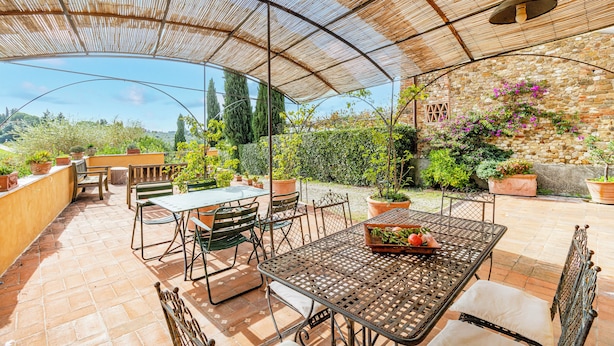 Un patio al aire libre con una zona de estar cubierta, muros de piedra y plantas en macetas.