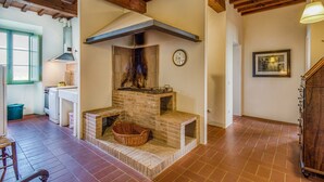 Una cocina rústica con chimenea de ladrillo, vigas de madera y un reloj en la pared.