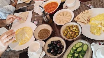 A breakfast buffet with various dishes including eggs, meats, olives, and bread.