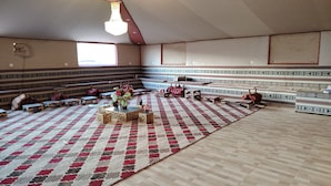 Une vaste salle dotée de gradins, d’un tapis à motifs et d’un lustre.