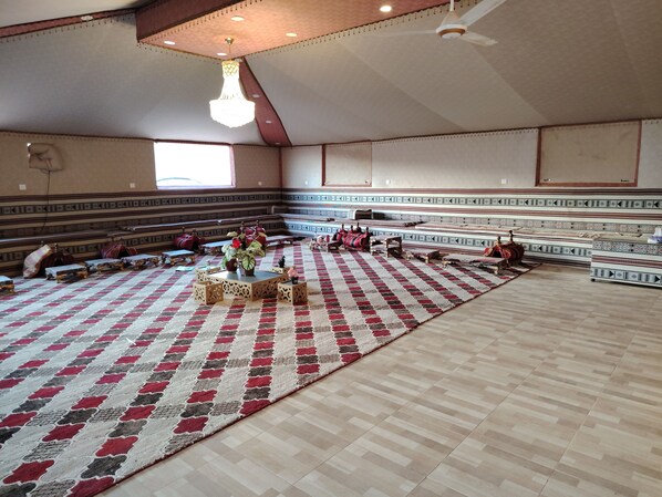 Une vaste salle dotée de gradins, d’un tapis à motifs et d’un lustre.