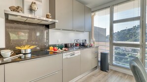 Eine moderne Küche mit einer Edelstahl-Dunstabzugshaube, einem eingebauten Geschirrspüler und einem Fenster mit Jalousien.