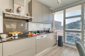 Eine moderne Küche mit einer Edelstahl-Dunstabzugshaube, einem eingebauten Geschirrspüler und einem Fenster mit Jalousien.
