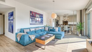 Ein modernes Wohnzimmer mit einer Eckcouch, einem Couchtisch und einem Essbereich im Hintergrund.