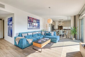 Ein modernes Wohnzimmer mit einer Eckcouch, einem Couchtisch und einem Essbereich im Hintergrund.