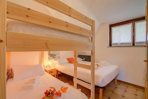 A bunk bed room with two beds, a window, and a nightstand with a lamp.