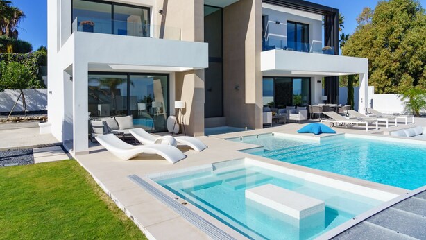 A modern two-story house with a swimming pool, outdoor seating, and a well-maintained lawn.
