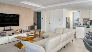 A modern living room with a sectional sofa, a flat-screen TV mounted on the wall, and a minimalist design.