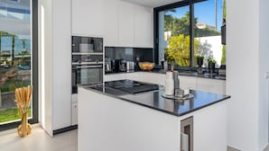 A modern kitchen with a large island, built-in appliances, and a view of the outdoors.