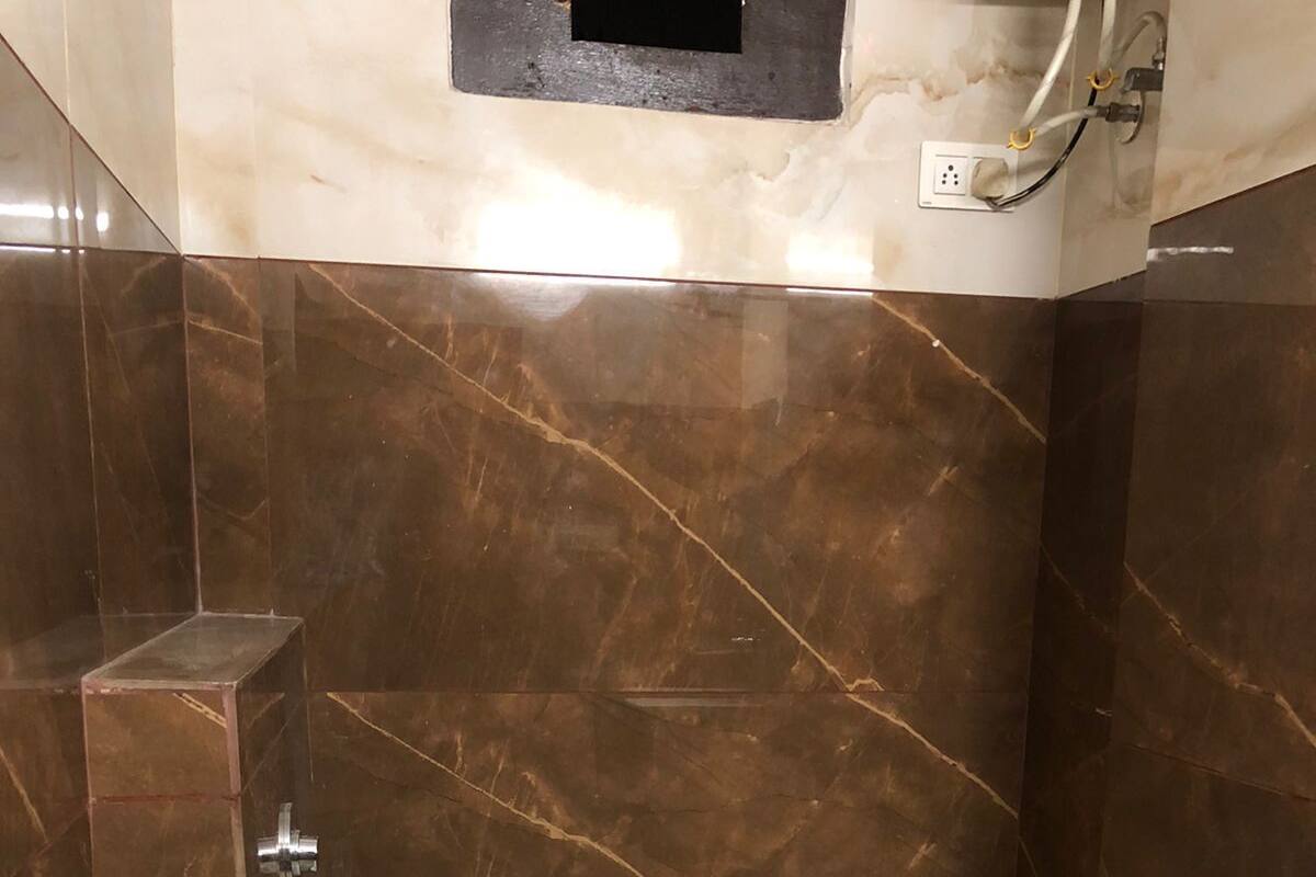 A small, modern bathroom with a toilet, a shower area, and marble walls.