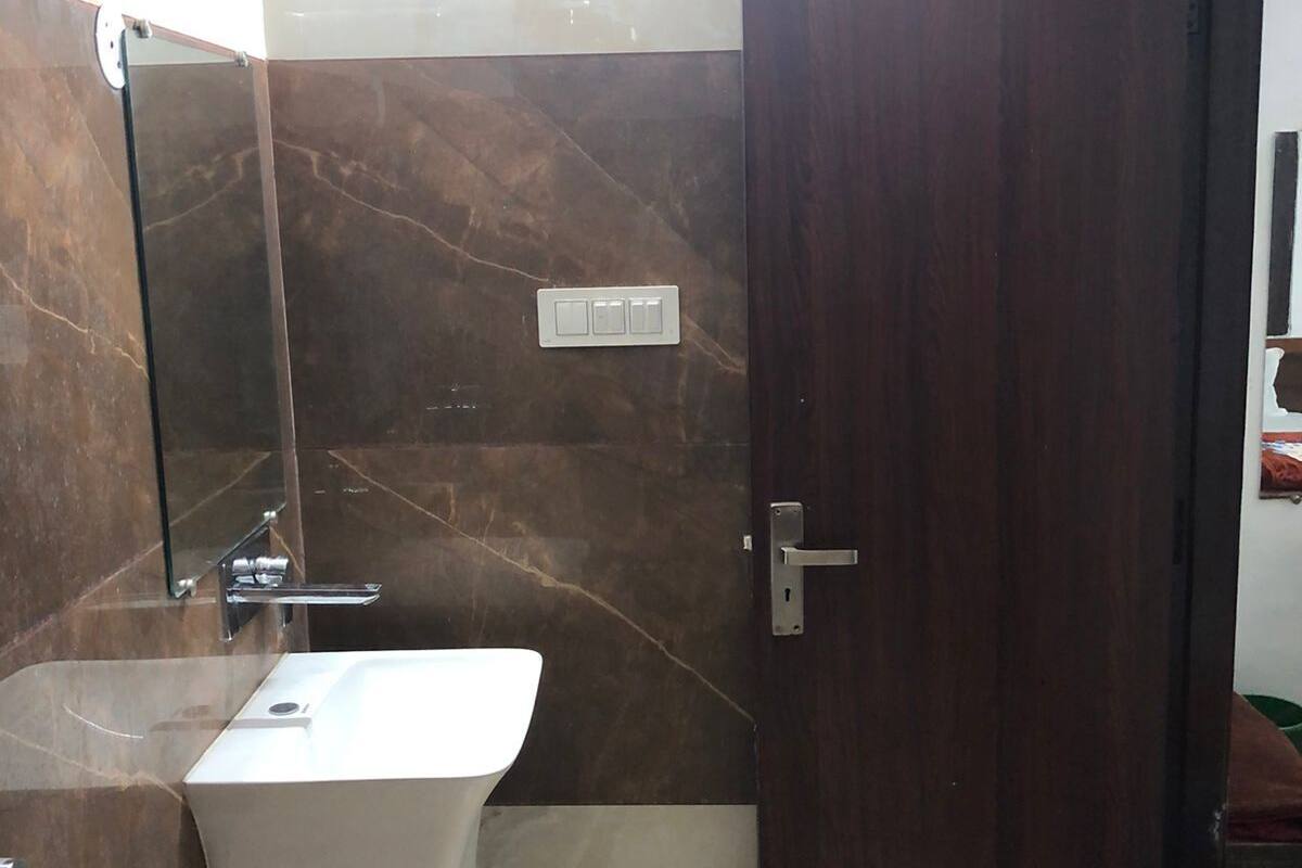 A bathroom with a marble wall, a white sink, a mirror, and a door.