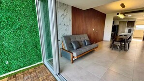 A modern living room with a sofa, a dining area, and a kitchen in the background. - Yuum Ha (Canc ún)