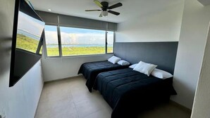 A bedroom with two beds, a ceiling fan, and a large window with a view of greenery. - Yuum Ha (Cancún)
