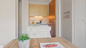A compact kitchen with a wooden door, a white towel, and a sign instructing to remove ski boots. - Crans-Montana center : Studio Ski 2 pers (Crans-Montana)