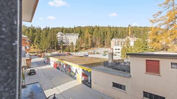 Un edificio con un murale sulla parete, un parcheggio e vista su una zona boschiva.
