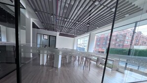 A modern office space with a glass partition, wooden flooring, and a view of buildings outside. - Loft Neoyorquino de Lujo en el Norte de Bogotá, Sauna, Turco, Gimnasio (Bogotá)