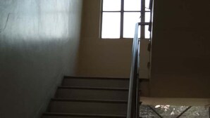 A staircase with metal railings leading to a landing. There is a window with a grid pattern on the landing. - HOTEL ARAWALI UDAIPUR CITY (Udaipur)
