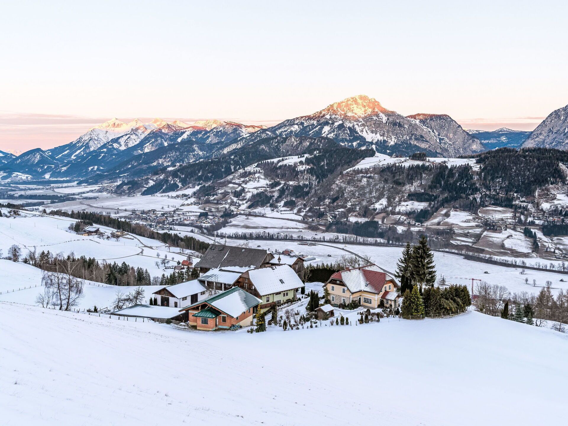 Un village enneigé, avec des maisons et une chaîne de montagnes en arrière-plan.