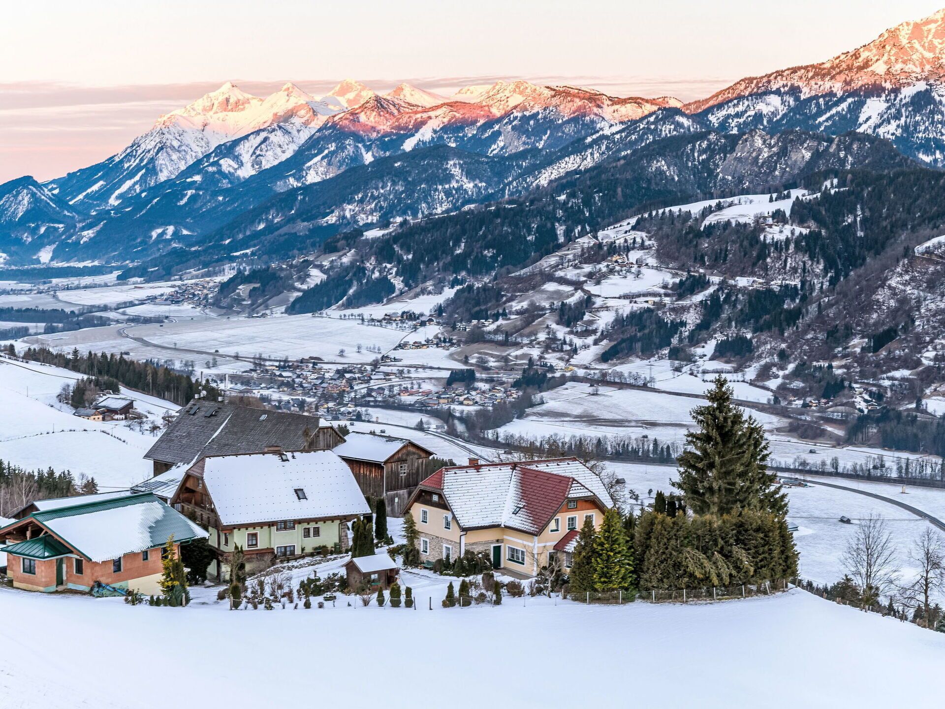 A snow-covered mountain village with traditional wooden houses and a river.