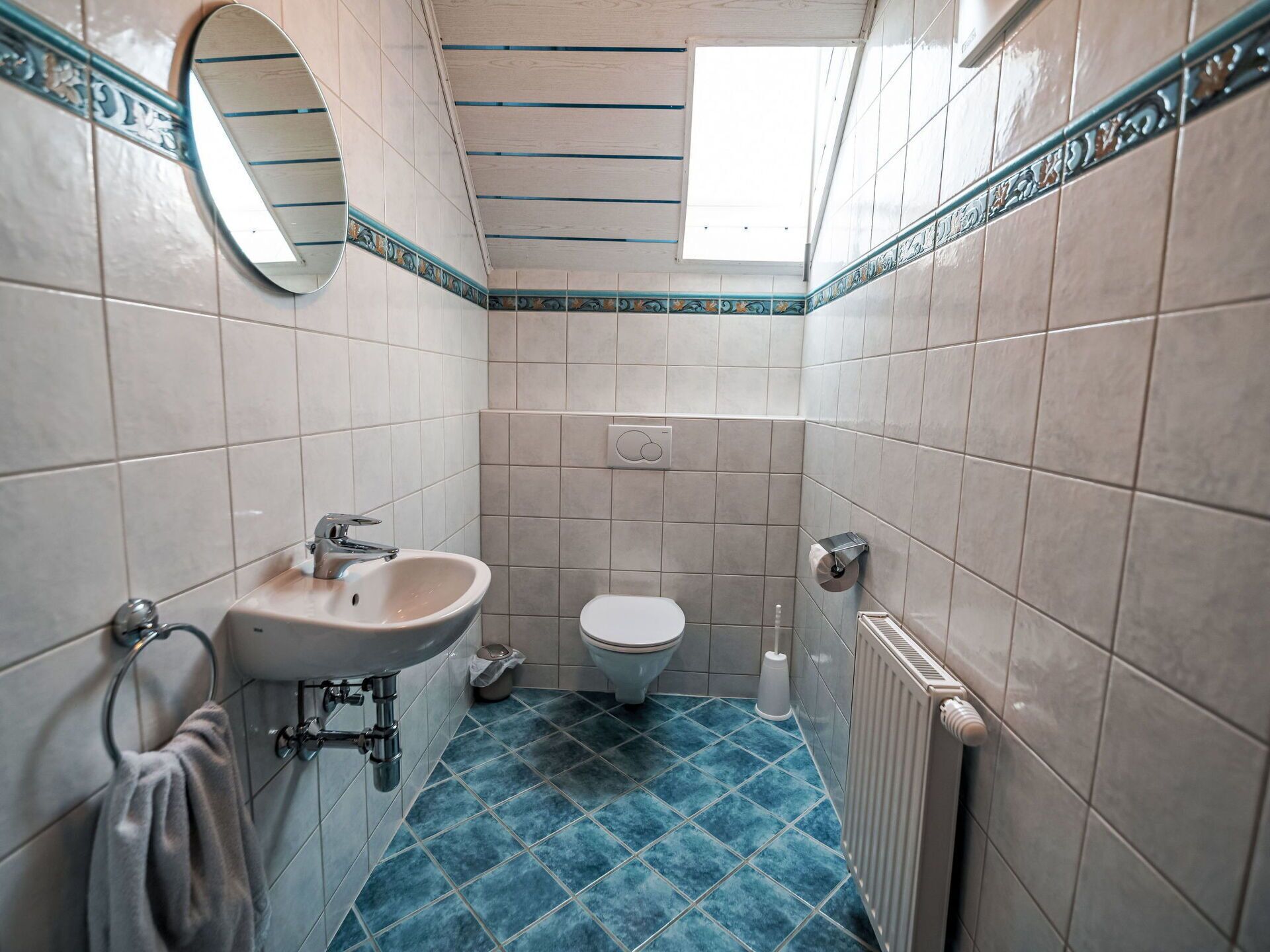 A bathroom with a sink, toilet, and a mirror.