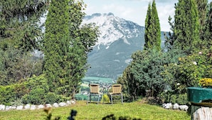 Uma área de estar tranquila ao ar livre, com duas cadeiras de vime voltadas para a vista da montanha.