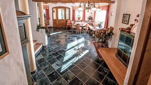 Uma sala de jantar espaçosa com teto de madeira, lustre e piso de azulejos.