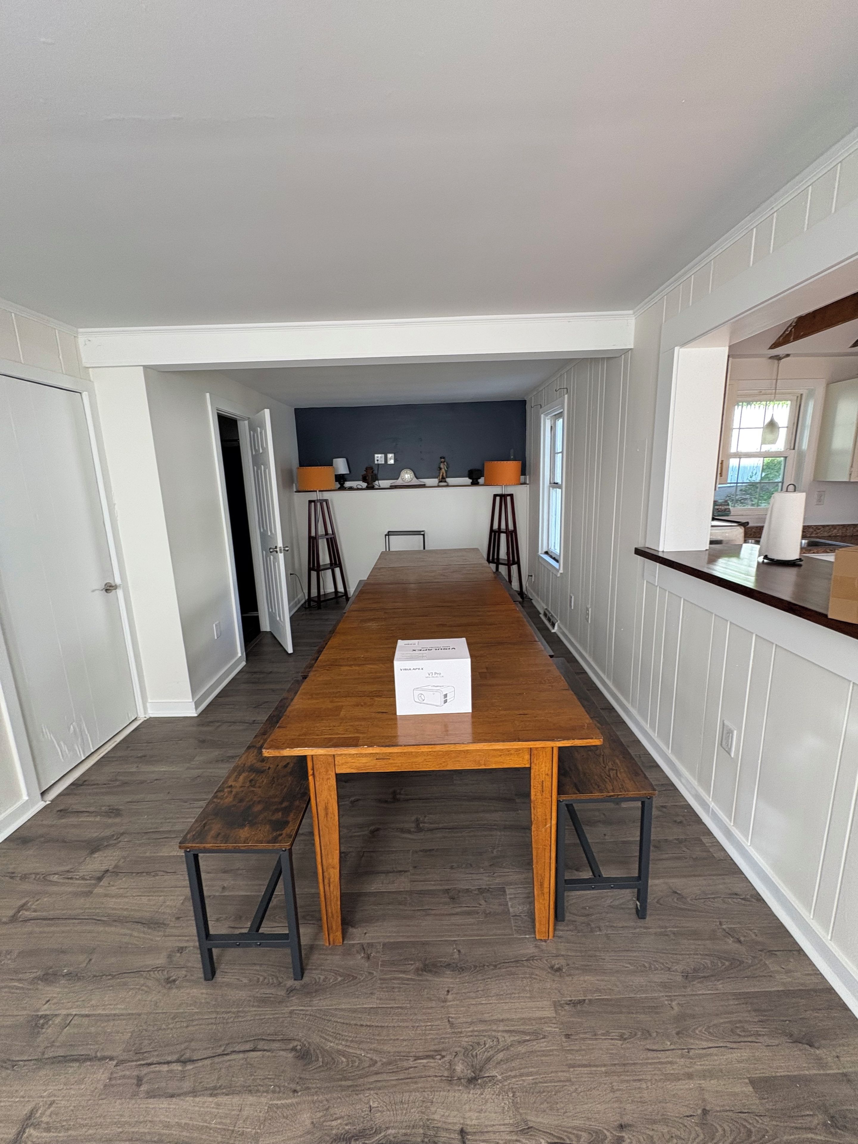 A spacious dining area with a long wooden table, two chairs, and a bench.