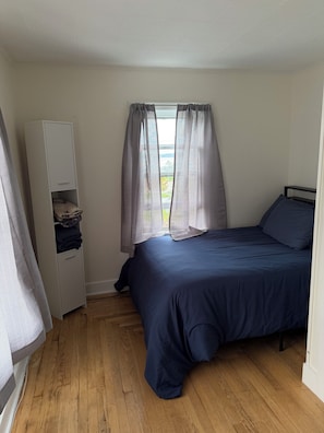 Un dormitorio con cama, armario y ventana con cortinas.