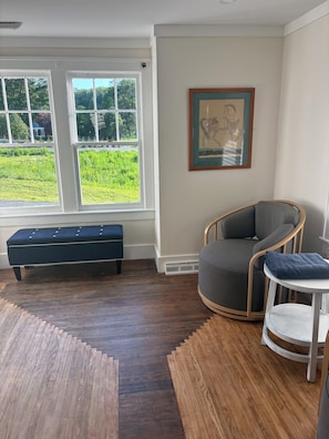 Una habitación con un ventanal grande, una banca, una silla y una mesita.
