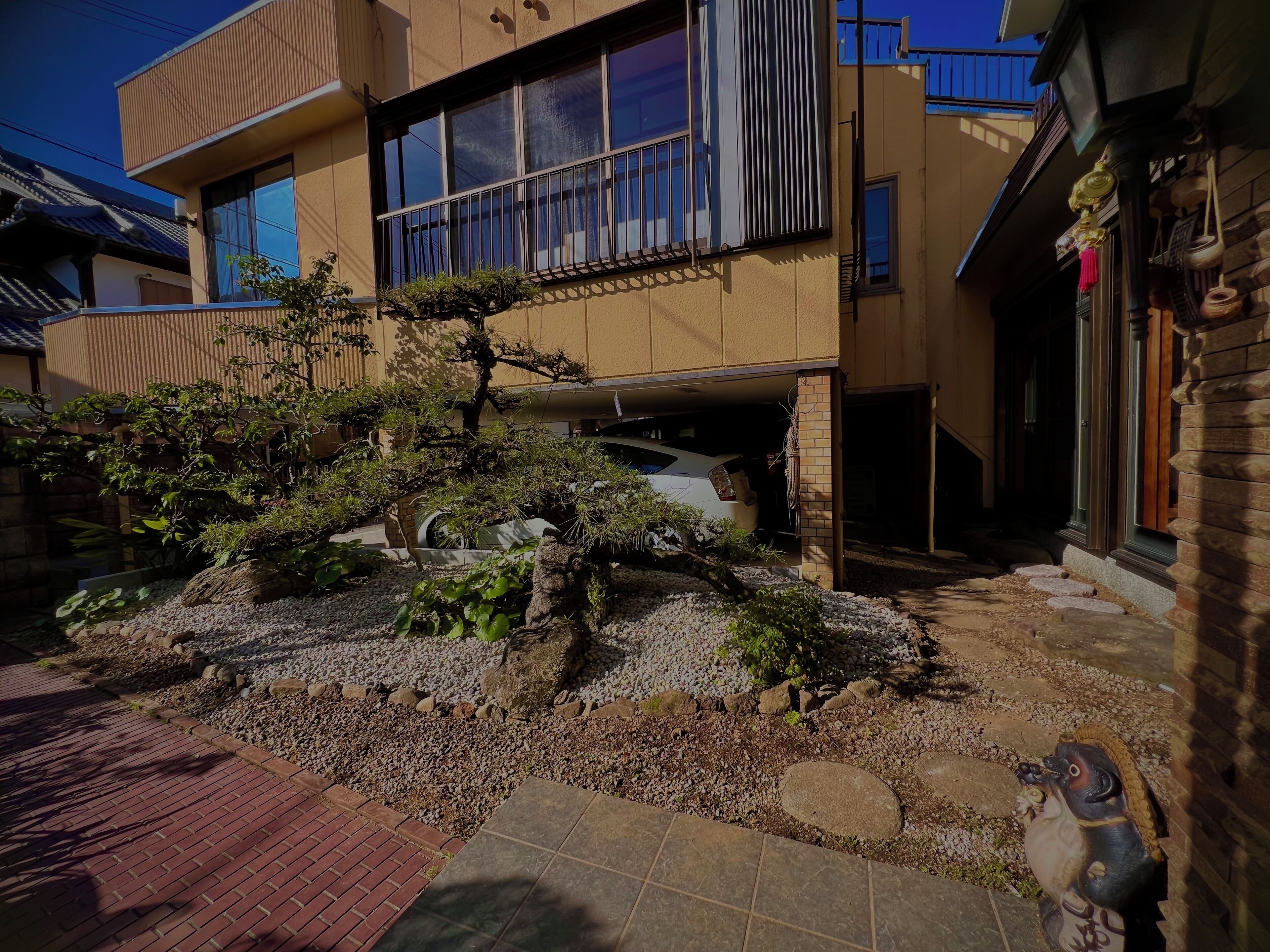 Un edificio moderno con un amplio ventanal y un pequeño jardín con rocas y plantas.