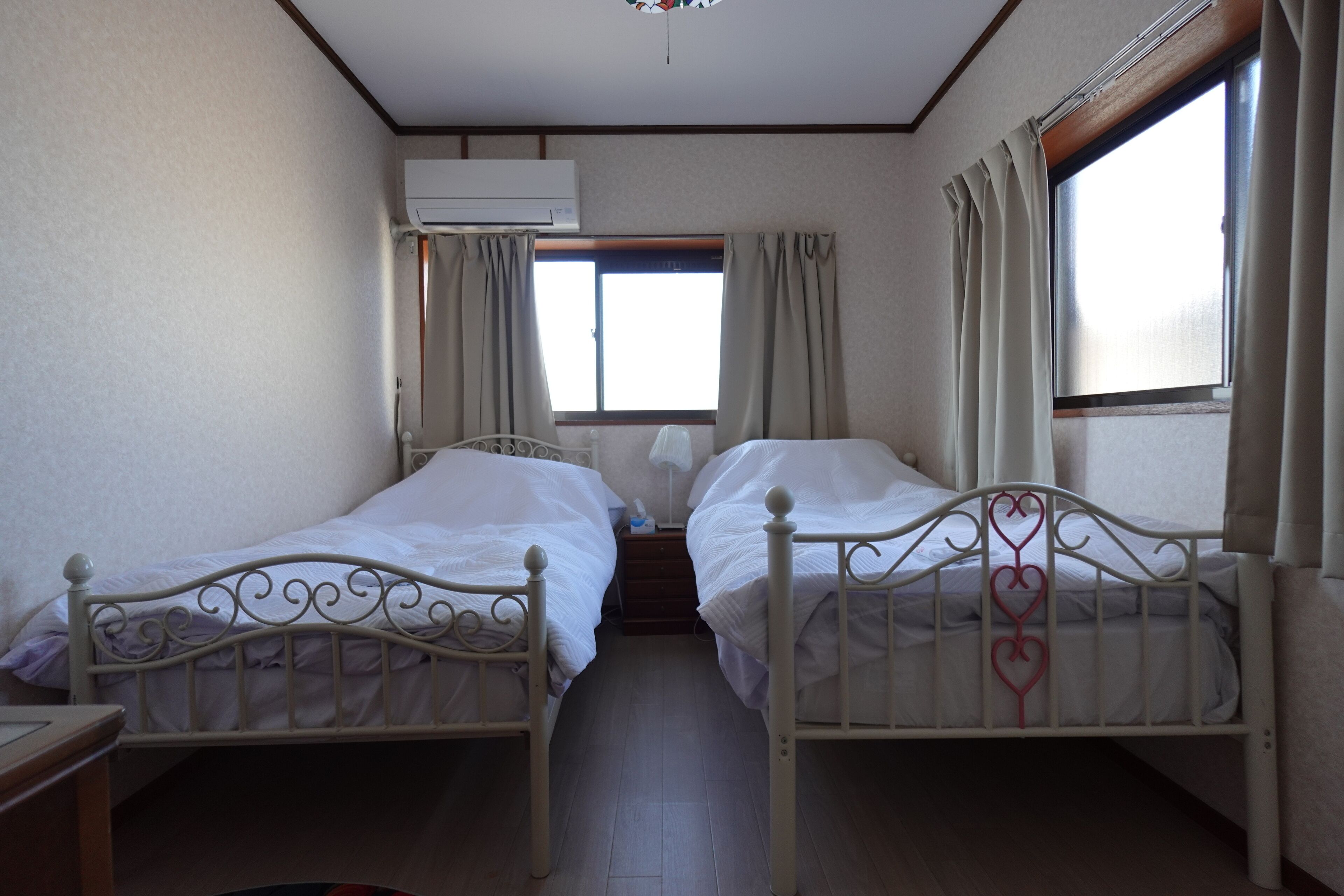 A twin room with two beds, a window, and an air conditioning unit.
