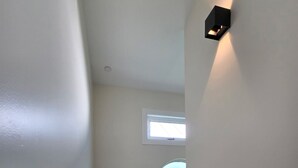 Eine Treppe mit Handlauf, einem kleinen Fenster und einer Wandleuchte.