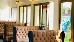 A restaurant with high-backed booths, pendant lighting, and large windows offering a view of the outdoors. - Amara Blue Resort (Mandera)