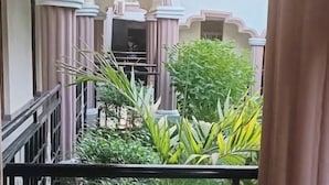 A balcony with a wrought iron gate, a view of a garden, and a building with classical architecture. - Amara Blue Resort (Mandera)