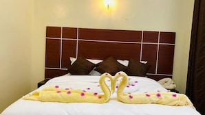 A hotel room with a neatly made bed, a wooden headboard, and a wall-mounted light fixture. - Amara Blue Resort (Mandera)