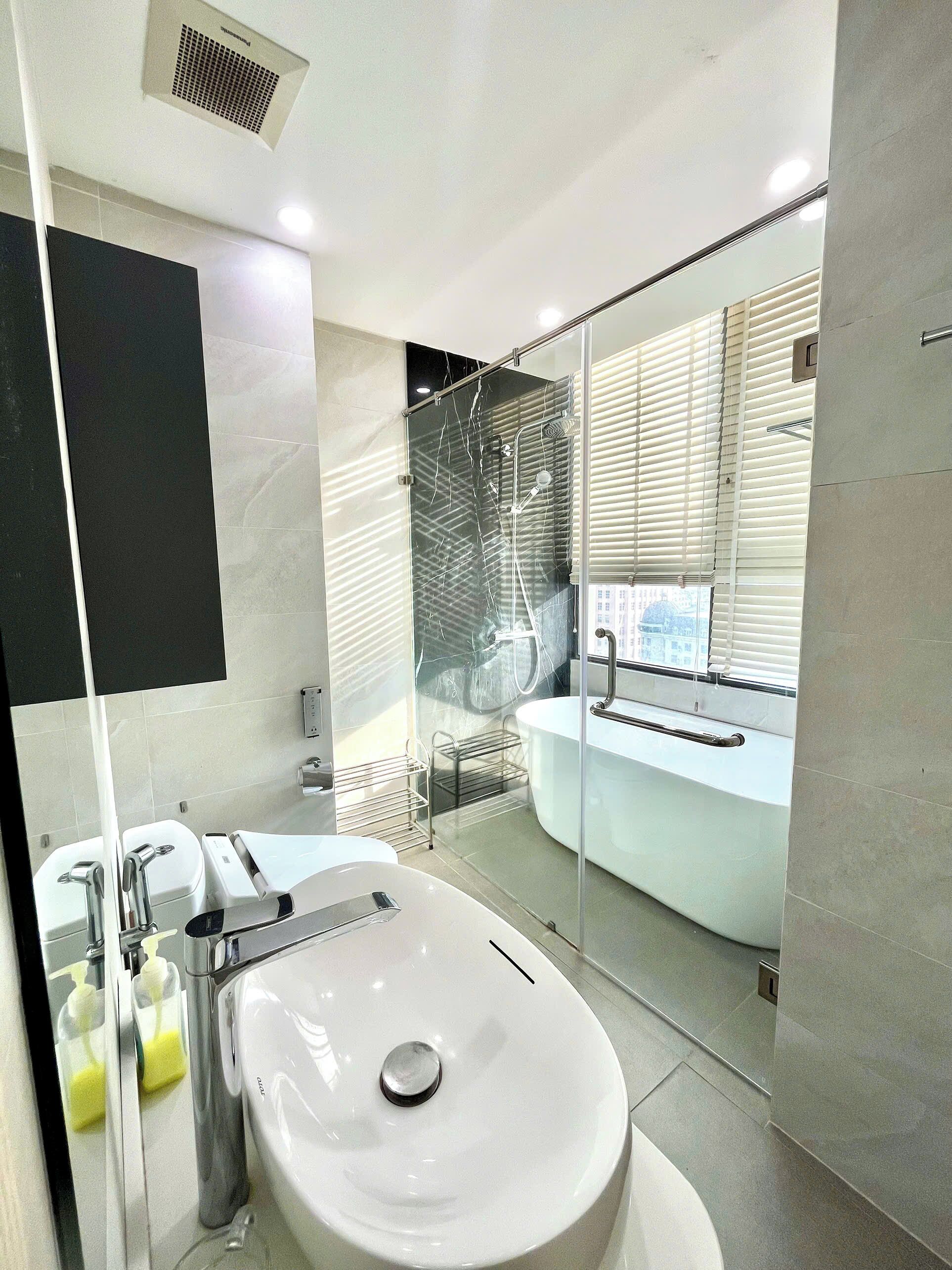 A modern bathroom with a large white sink, a glass-enclosed shower, and a bathtub.