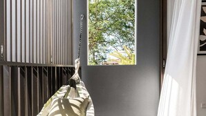 A hammock chair in a room with a view of trees through a window. - Aurelia Byron- Jonson Lane (Byron Bay)