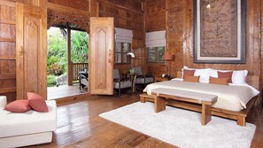 Una habitación de madera con una cama, un escritorio y una silla. Hay un sofá blanco y una alfombra blanca.