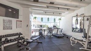 Une salle de sport équipée de matériel d’exercice, d’un banc, d’haltères et d’un tapis de course.