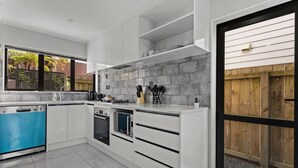 A modern kitchen with white cabinetry, a built-in oven, and a dishwasher. - Modern Townhouse with Parking nr Airport & Manukau (Auckland South)