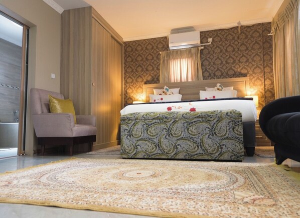 A hotel room with a bed, a sofa, a patterned rug, and a window with curtains. - kebo events &self catering apartments (Malotwana)