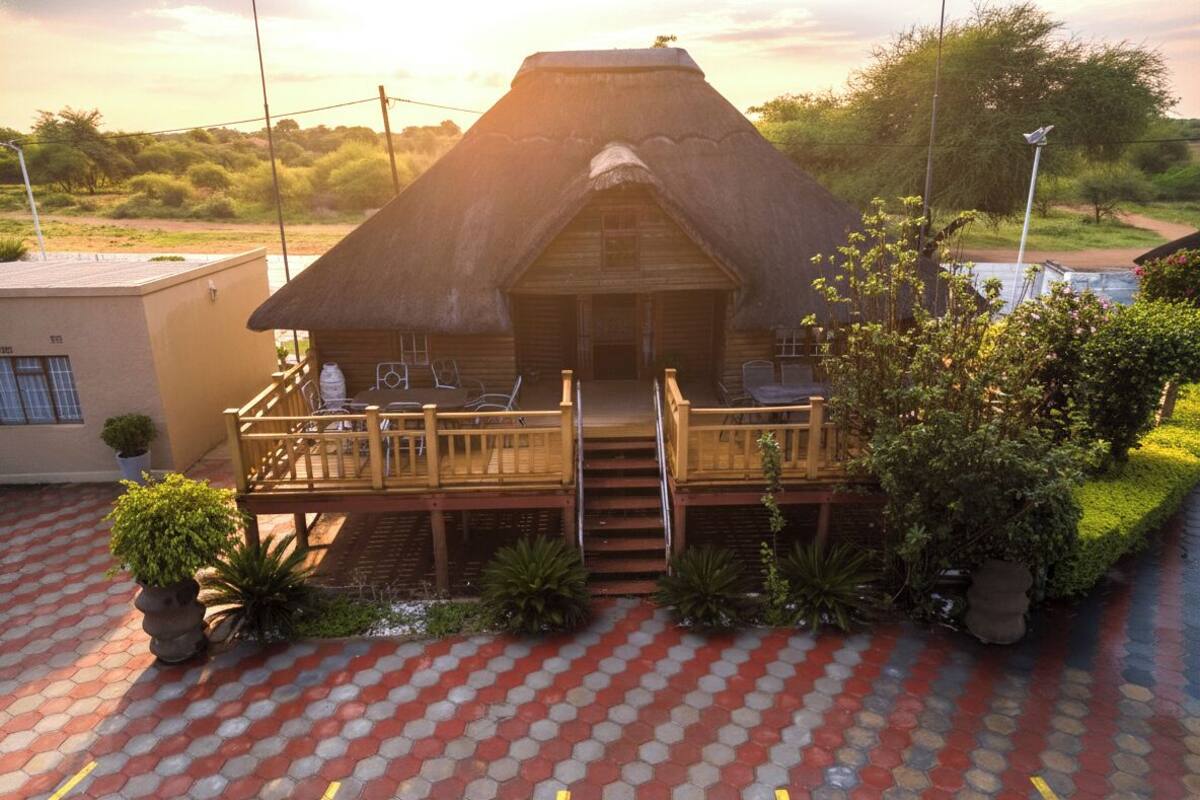 A thatched-roof building with a wooden deck and outdoor seating.