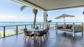 Un espacio al aire libre cubierto con una terraza de madera, una mesa redonda con sillas, un sofá y un paraguas grande.