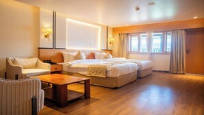 Una habitación de hotel con una cama grande, un sofá, una mesa de centro de madera y un escritorio.