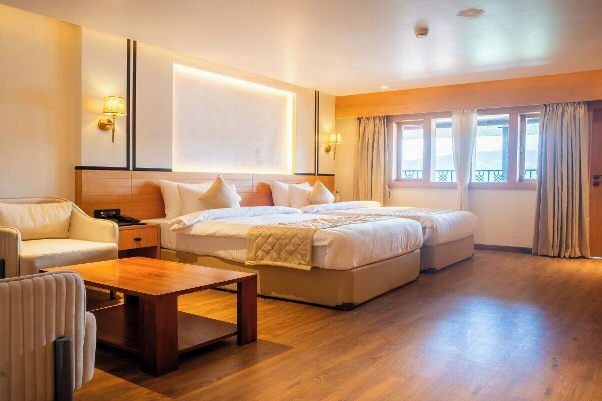 A hotel room with a large bed, a sofa, a wooden coffee table, and a desk.