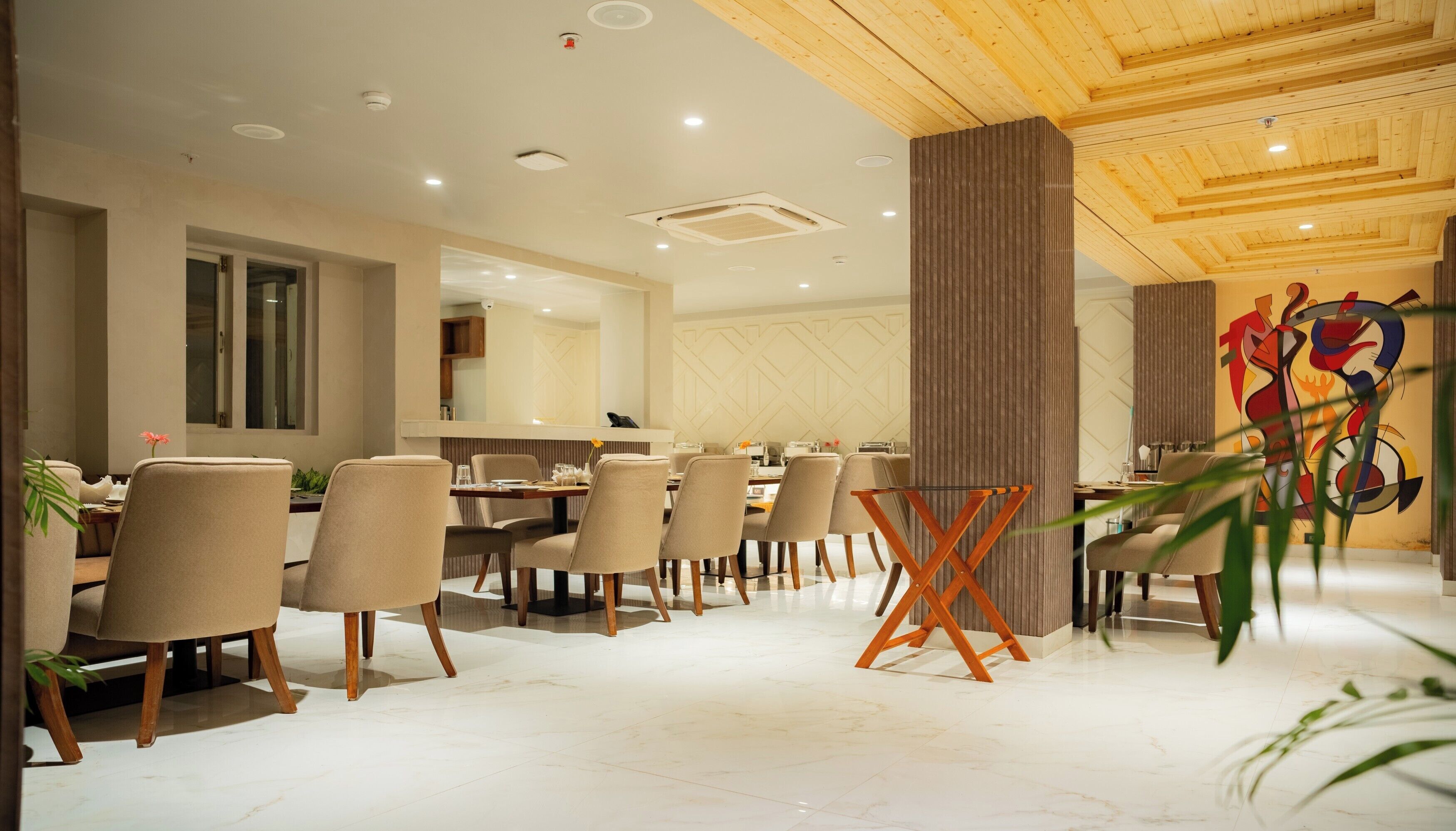 A modern dining area with a wooden ceiling, beige chairs, and a central table.